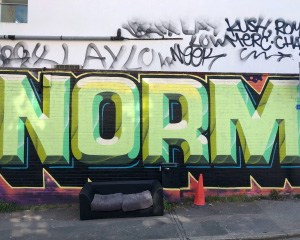 [Translate to English:] Grünes "Norm"-Graffiti an Häuserwand.