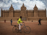 A boy rides a bicycle in front of the Great Mosque of Djenné, designated a World Heritage Site by the United Nations Educational, Scientific and Cultural Organization (UNESCO) in 1988 along with the old town of Djenné, in the central region of Mali.