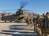 Soldaten mit Gepäck laufen auf einen wartenden Hubschrauber zu
