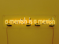 Installation des Schriftzugs „a mentsh is a mentsh“ in leuchtenden Buchstaben auf gelbem Hintergrund