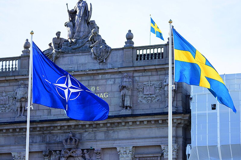 Eine NATO Flage und eine schwedische Flagge wehen vor einem alten Gebäude