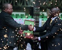 Kenya's new president William Ruto, right, seen behind fountain fireworks, shakes hands with outgoing President Uhuru Kenyatta, left, as he is sworn in to office at a ceremony held at Kasarani stadium in Nairobi, Kenya Tuesday, Sept. 13, 2022.