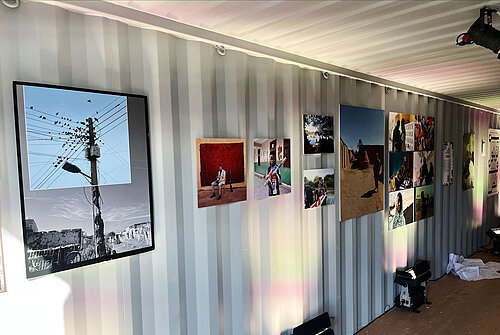 Pictures from the photography exhibition “Postcards from Khartoum” hang on a container wall.