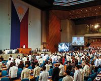 Personen stehen in Saal mit philippinischer Flagge