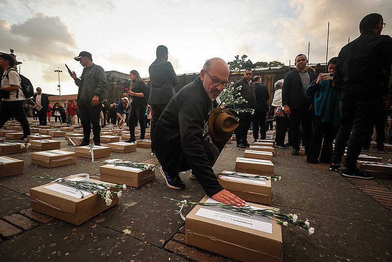 Menschen legen Blumen auf braunen Kästen ab zum Protest gegen die Ermordung sozialer Aktivist*innen