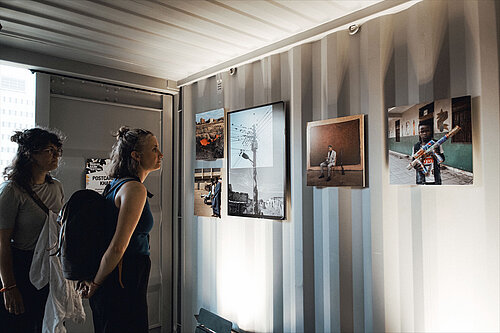 Two people look at the pictures in the exhibition “Postcards from Khartoum.”