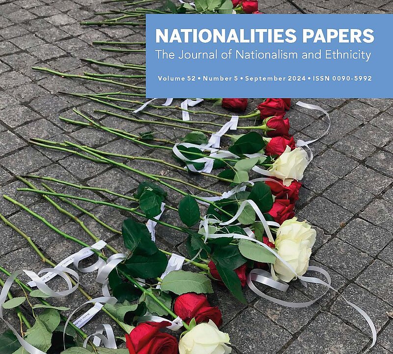 Cover des Journals Nationalities Papers mit einem Bild von weißen und roten Rosen, an die jeweils kleine Papierstreifen mit Nachrichten gebunden sind, die auf einem Steinboden liegen