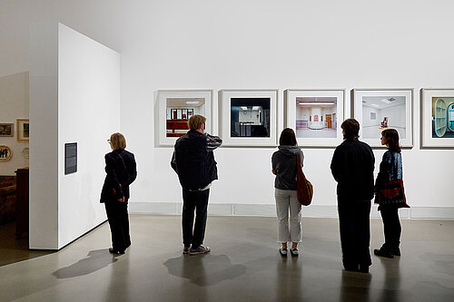 Several people are looking at pictures in an exhibition.