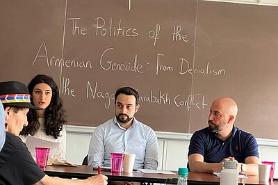 Vier Personen sitzen an Tischen. Im Hintergrund steht an einer Tafel "The Politics of the Armenian Genocide: From Denialism the Nagorno-Karabakh Conflict"