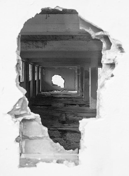 Black-and-white photo of a large hole in a wall