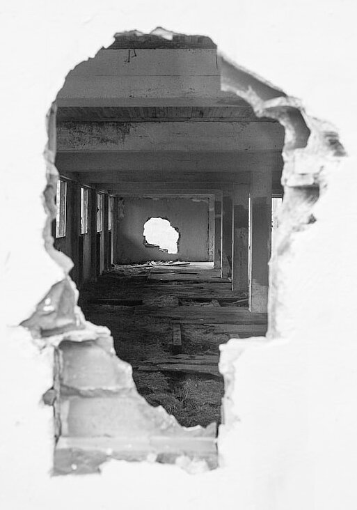 Schwarz-Weiß Bild eines großen Lochs in einer Wand
