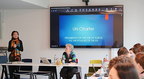 Xinyu Yuan and Kerstin Leitner; the presentation slide "UN Charter" and PRIF audience in background