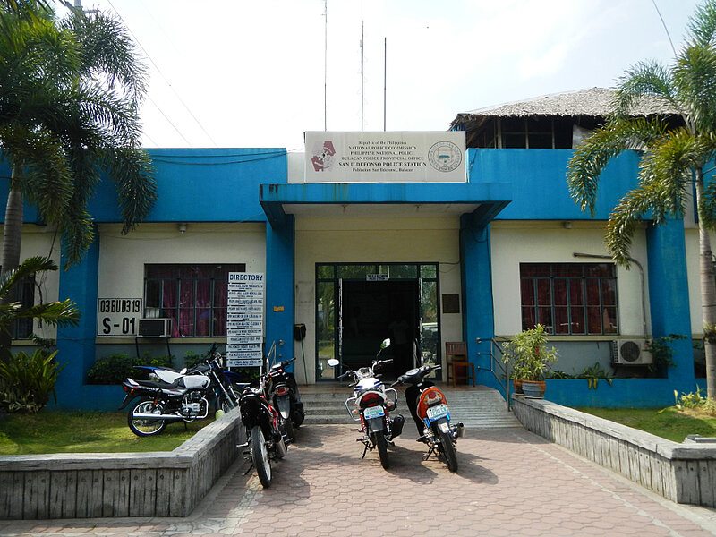 Blue and white building with palm trees and several motorbikes parked in front of it