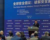 Ein Mann steht auf einer Bühne vor einem Publikum. Auf der Wand hinter ihm steht „The Global Security Initiative: Chinas proposal for So...“
