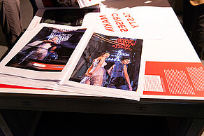 Pictures and texts are spread out on a table. The pictures show several people in unusual clothing.